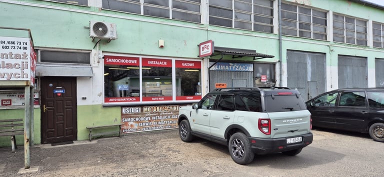 White SUV parked outside a light green storefront with red signage and red awning in an urban area