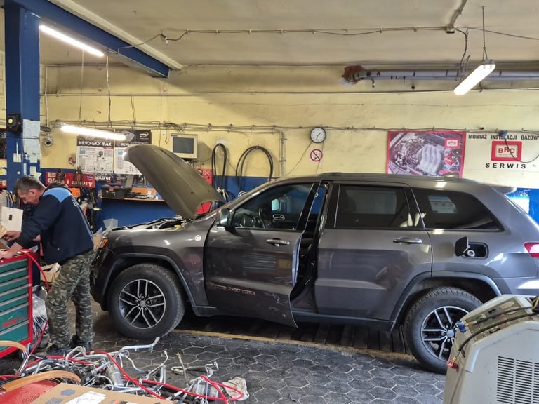 Gray SUV with open door and hood in a car service garage workshop